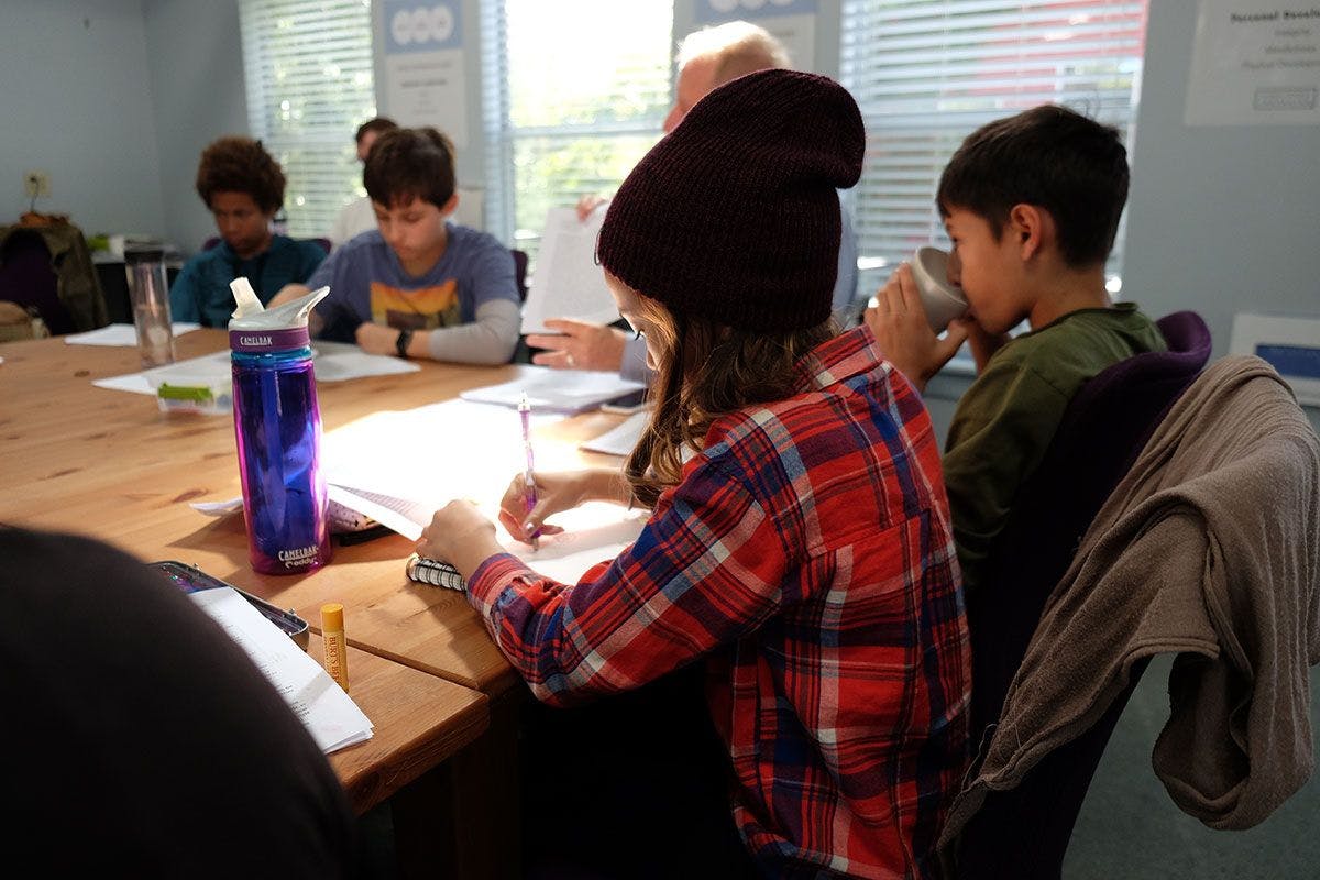 teens sitting at a table writing and discussing