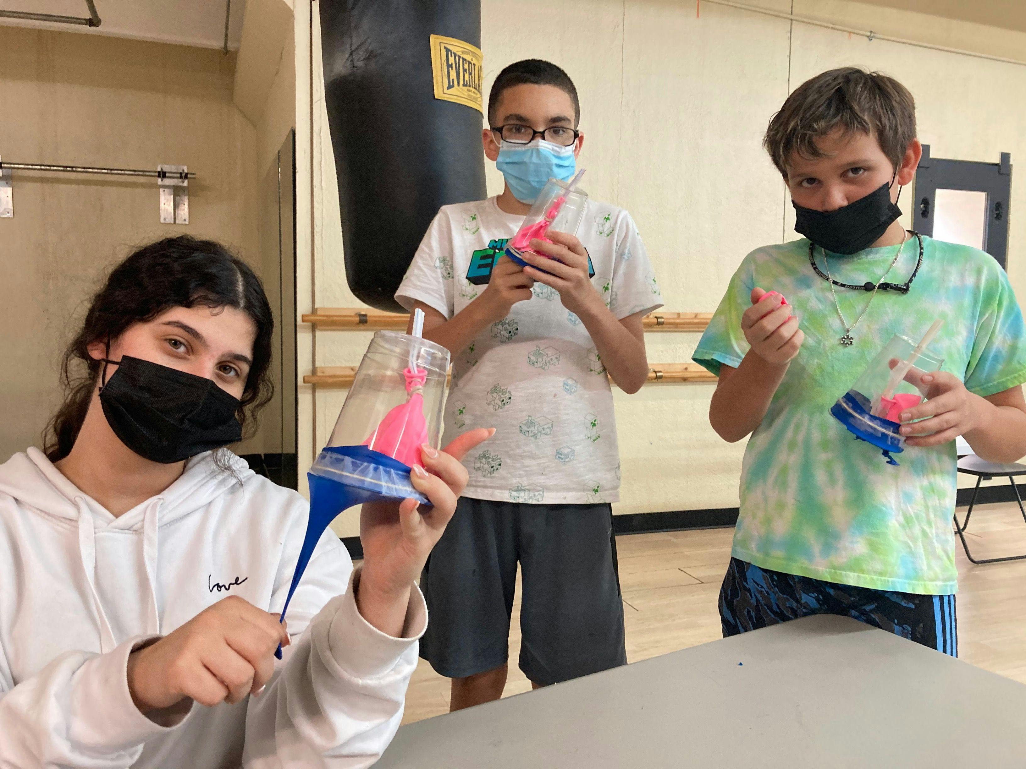 three Guidepost Academy North Scottsdale teenagers holding their projects while posing for the camera