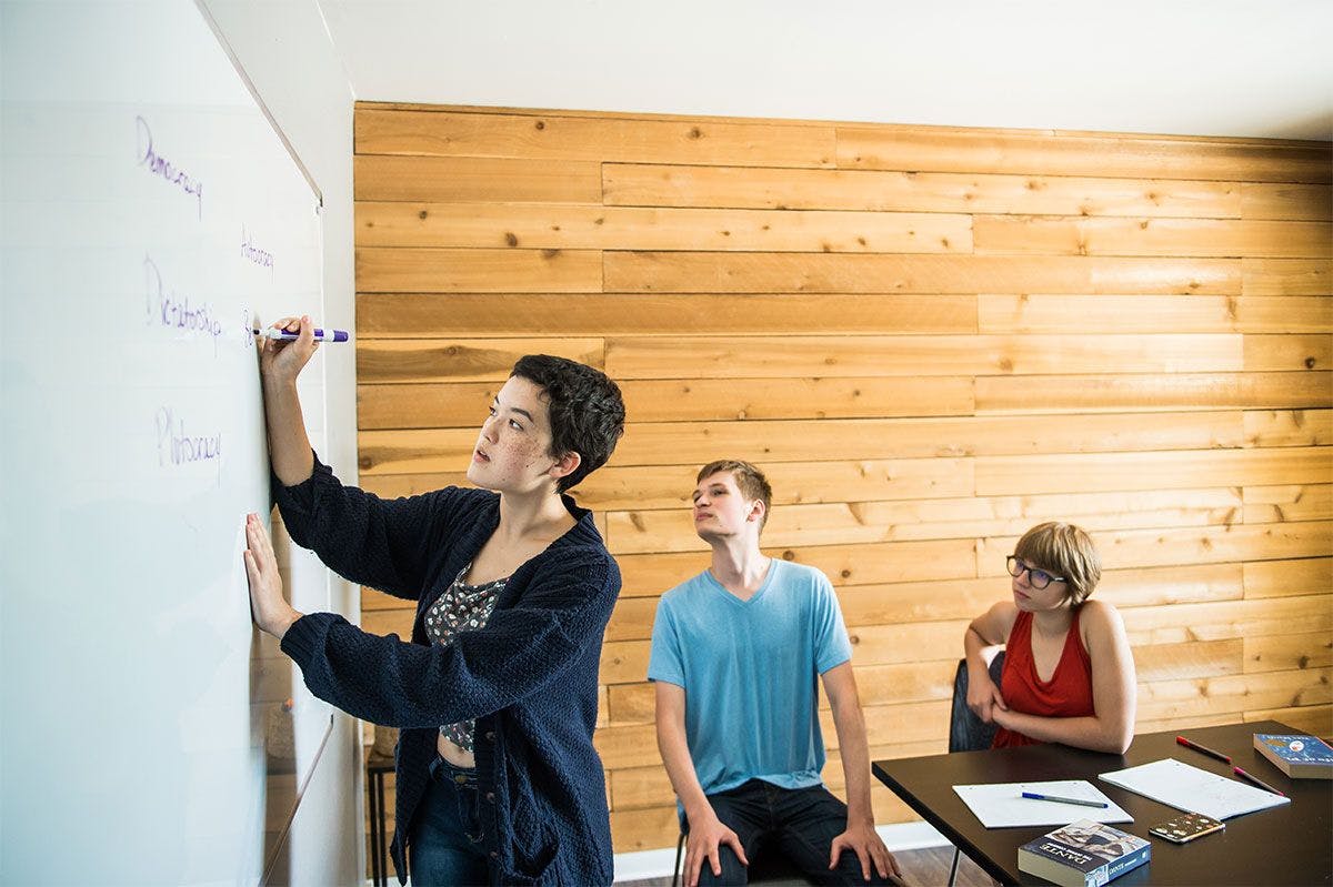 ati museum mile student writing on a whiteboard with other students